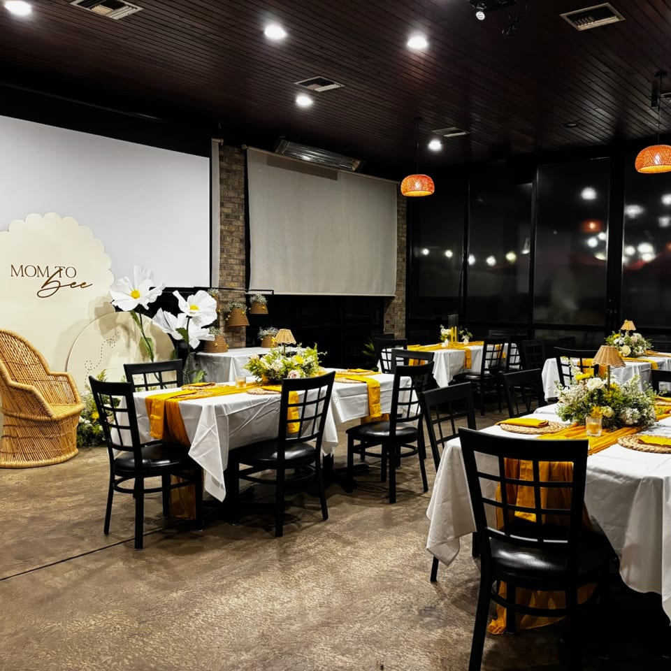Restaurant dining room set for a "Mom to Bee" baby shower with yellow and white decor.