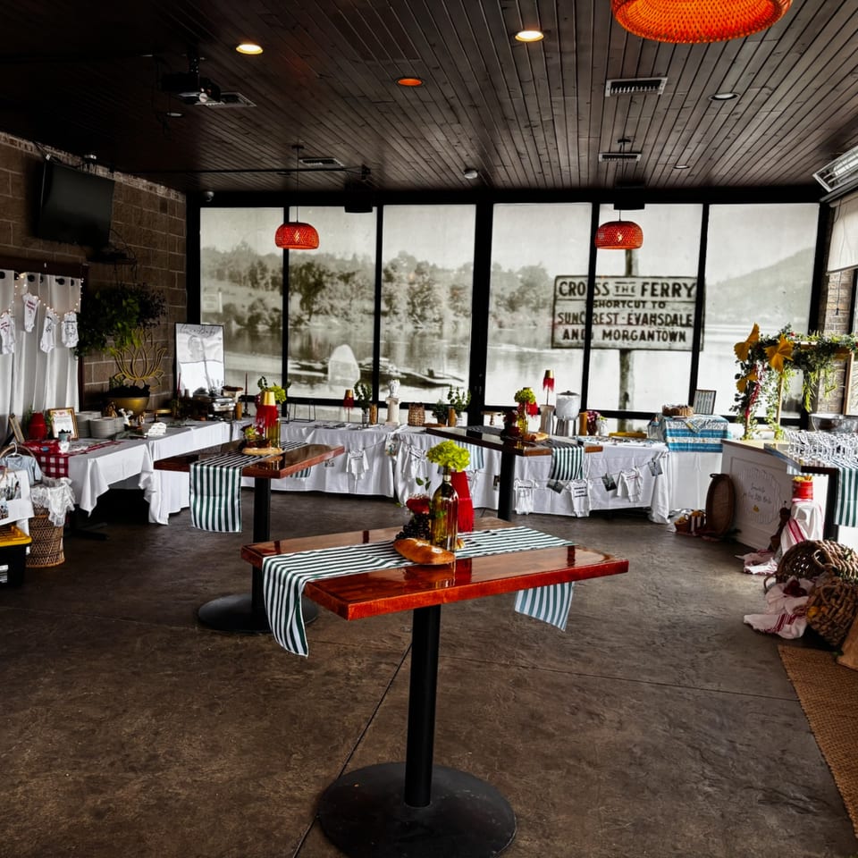A restaurant interior with buffet tables, high-top tables, and large windows overlooking a river.