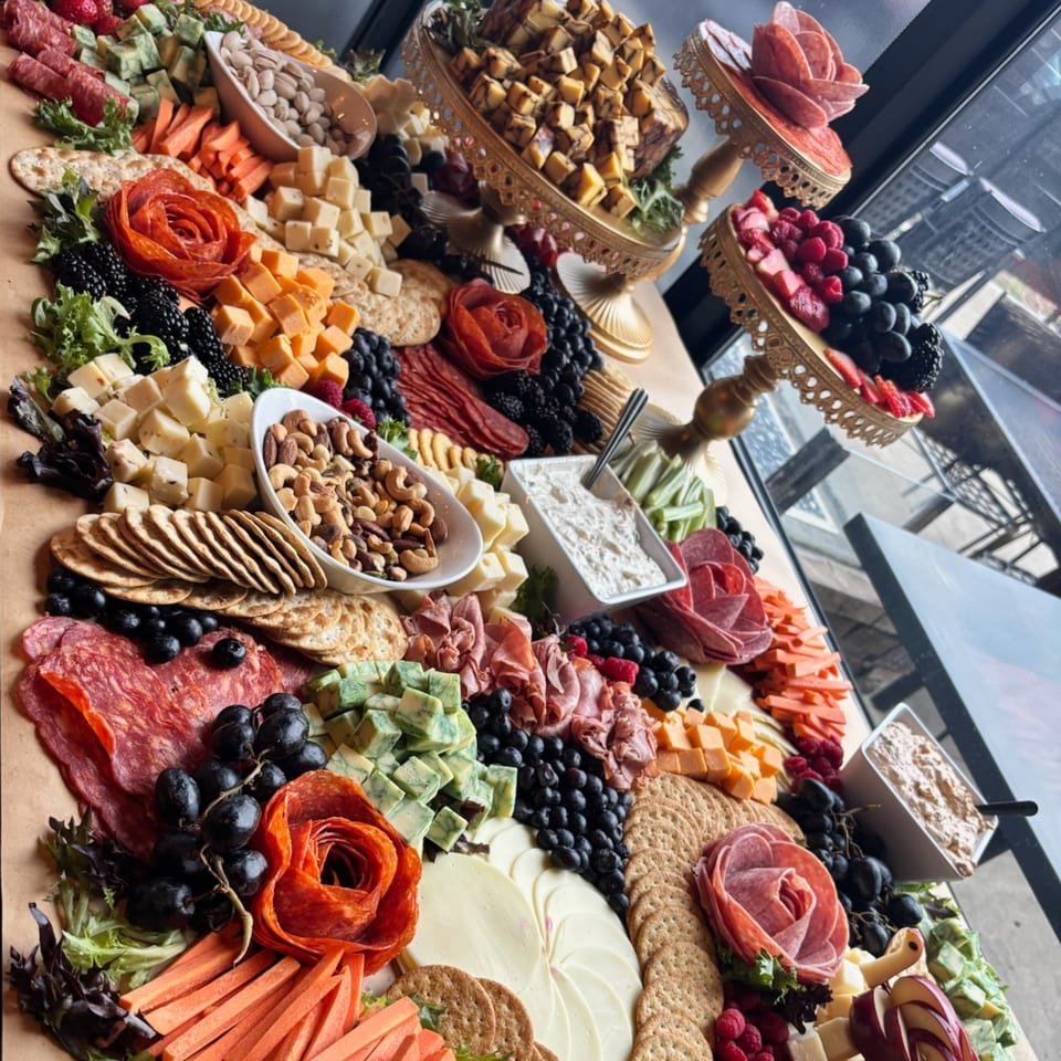 A lavish charcuterie board overflowing with cheeses, meats, fruits, nuts, crackers, and dips.